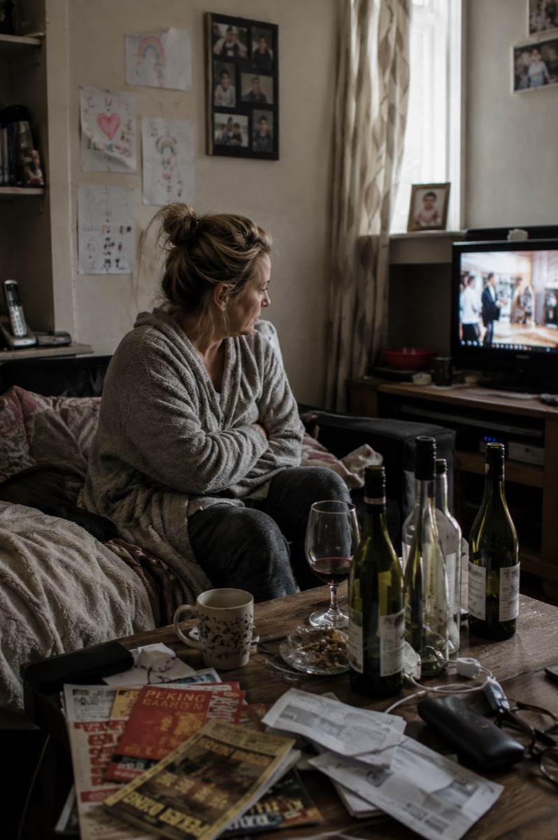 A person sitting alone with a drink while considering the need for alcohol treatment