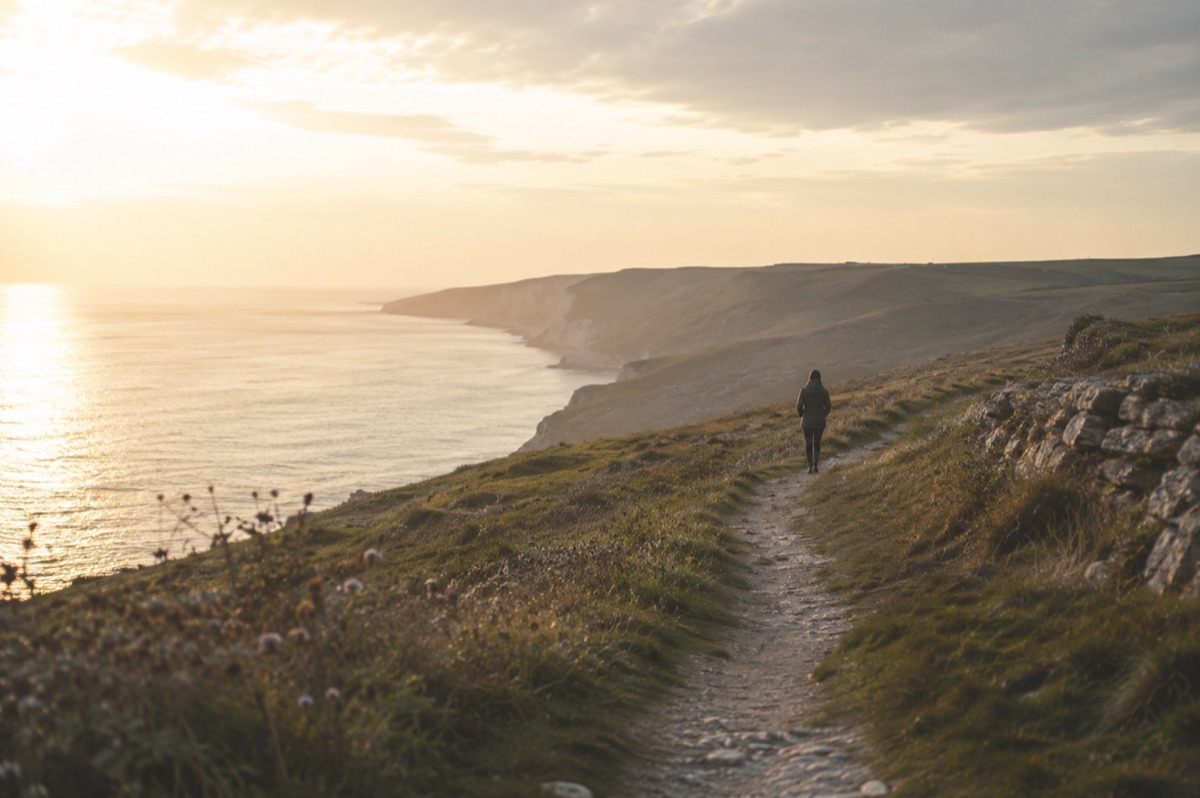A person walking along a quiet coastal path during recovery